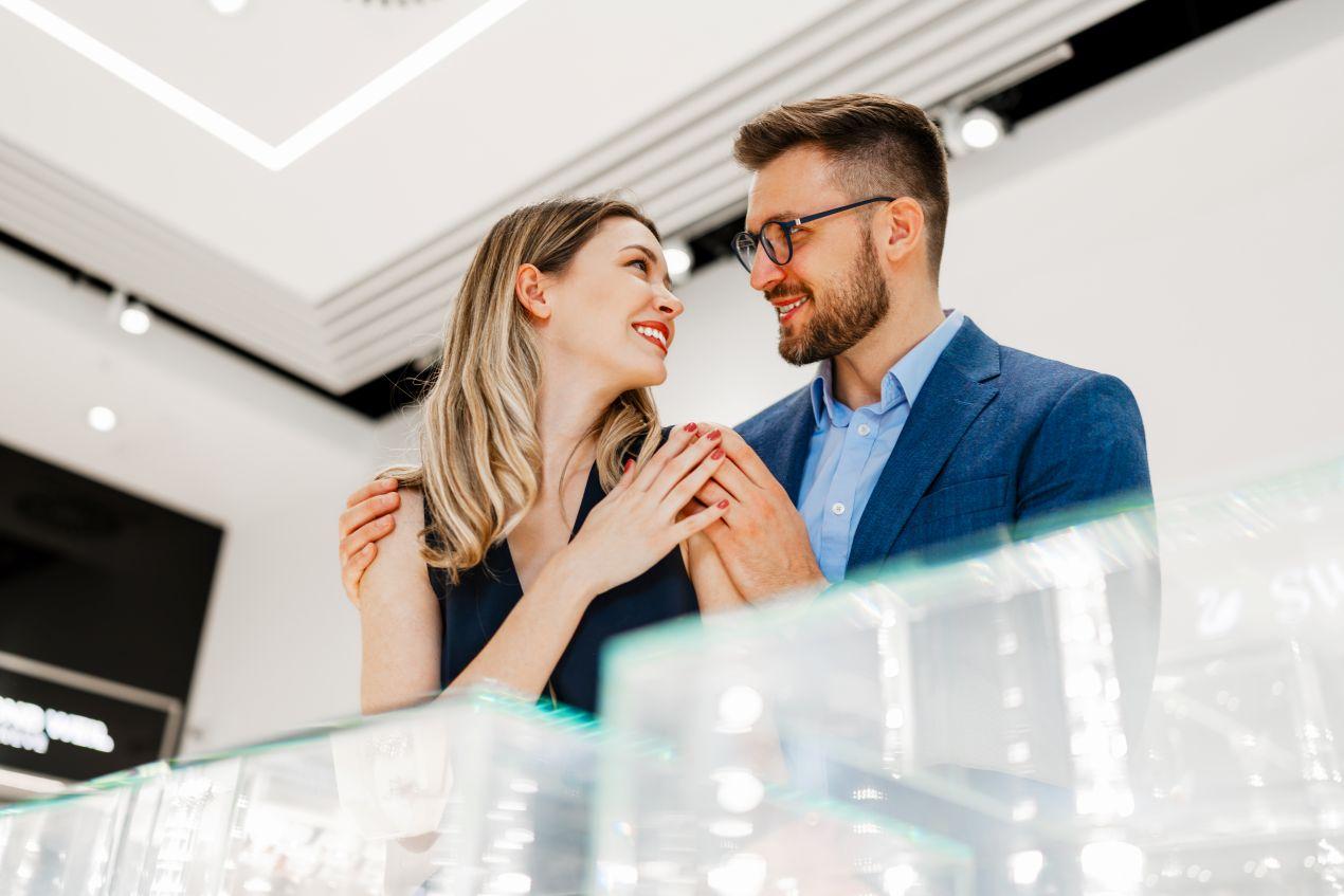 Junges Paar steht beim Juwelier und entscheidet sich gemeinsam fuer passende Partnerringe mit persoenlicher Bedeutung