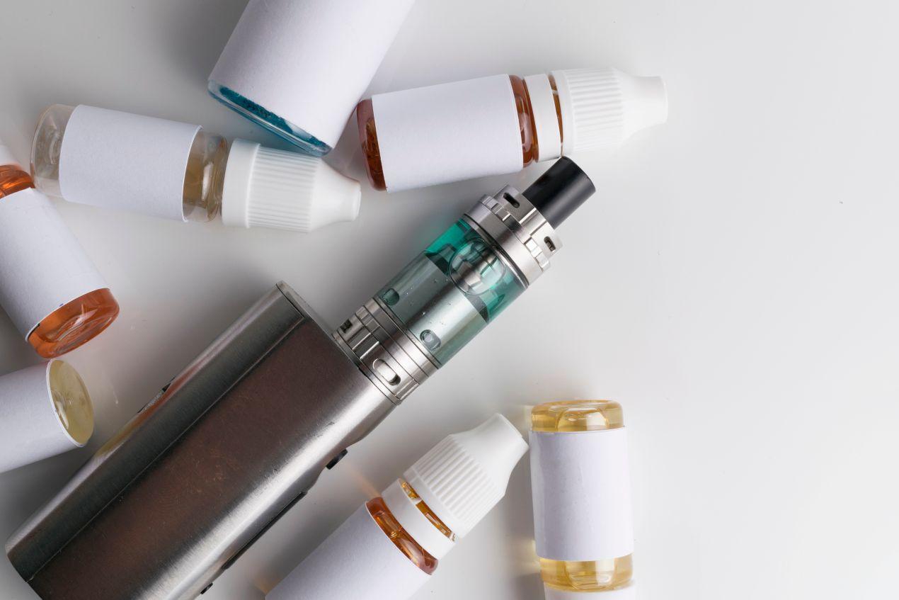 E-Zigarette mit mehreren Nachfüllflaschen Elfliq Liquid in verschiedenen Farben auf weißem Hintergrund