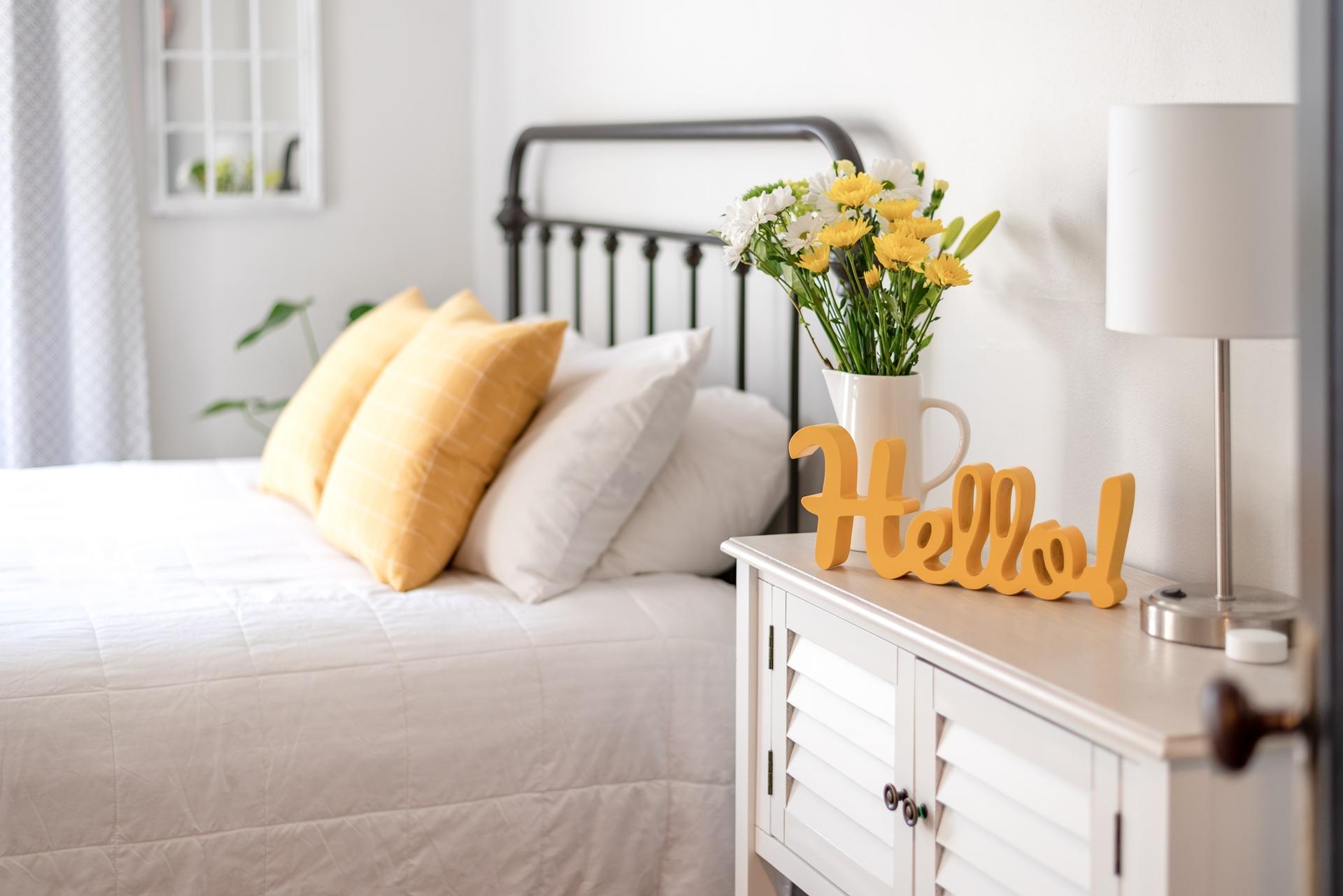 Helles Schlafzimmer mit gelben Kissen und frischen Blumen | Bettbank kaufen