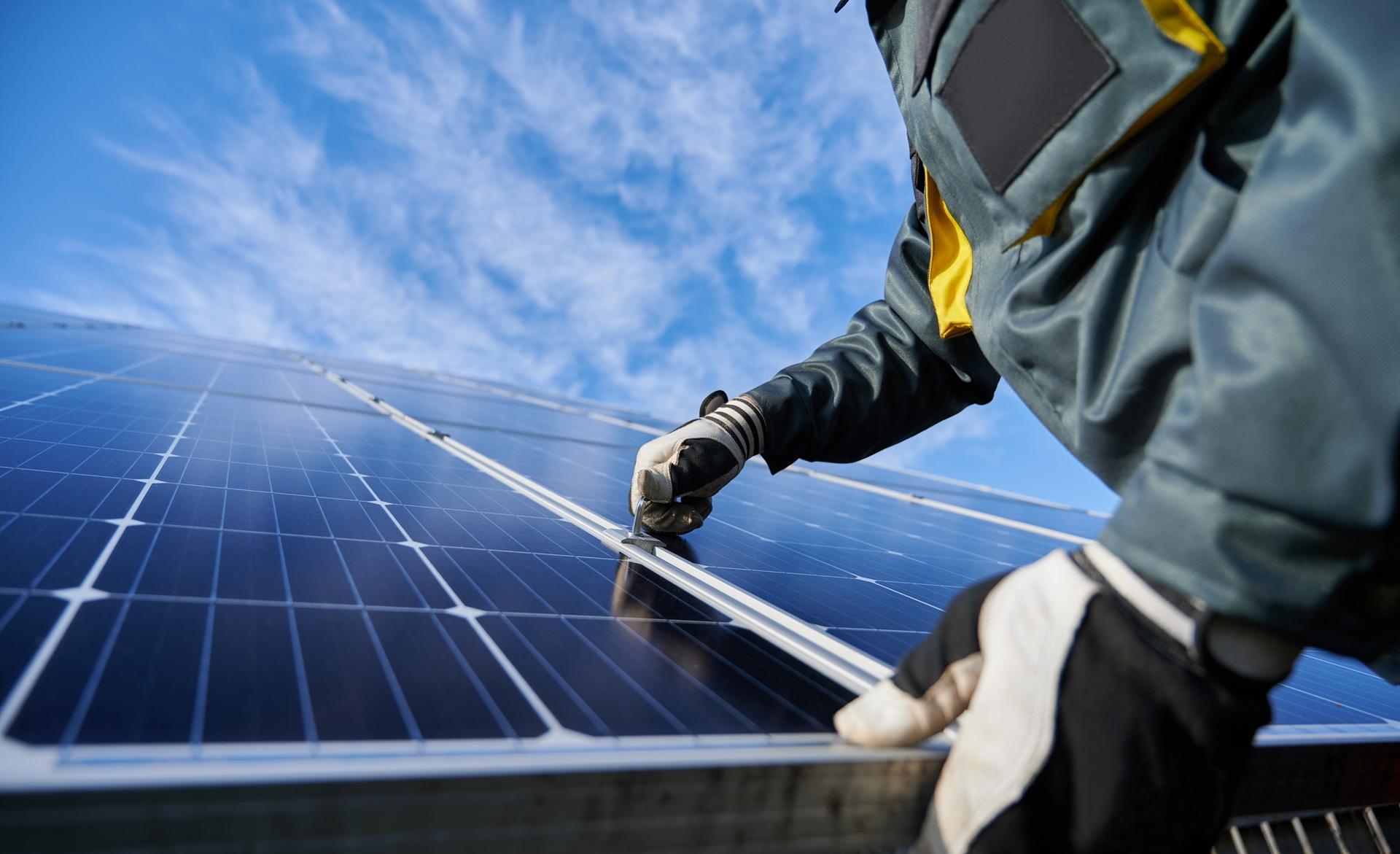 Handwerker montiert Solarpanel unter blauem Himmel | PV Großhandel